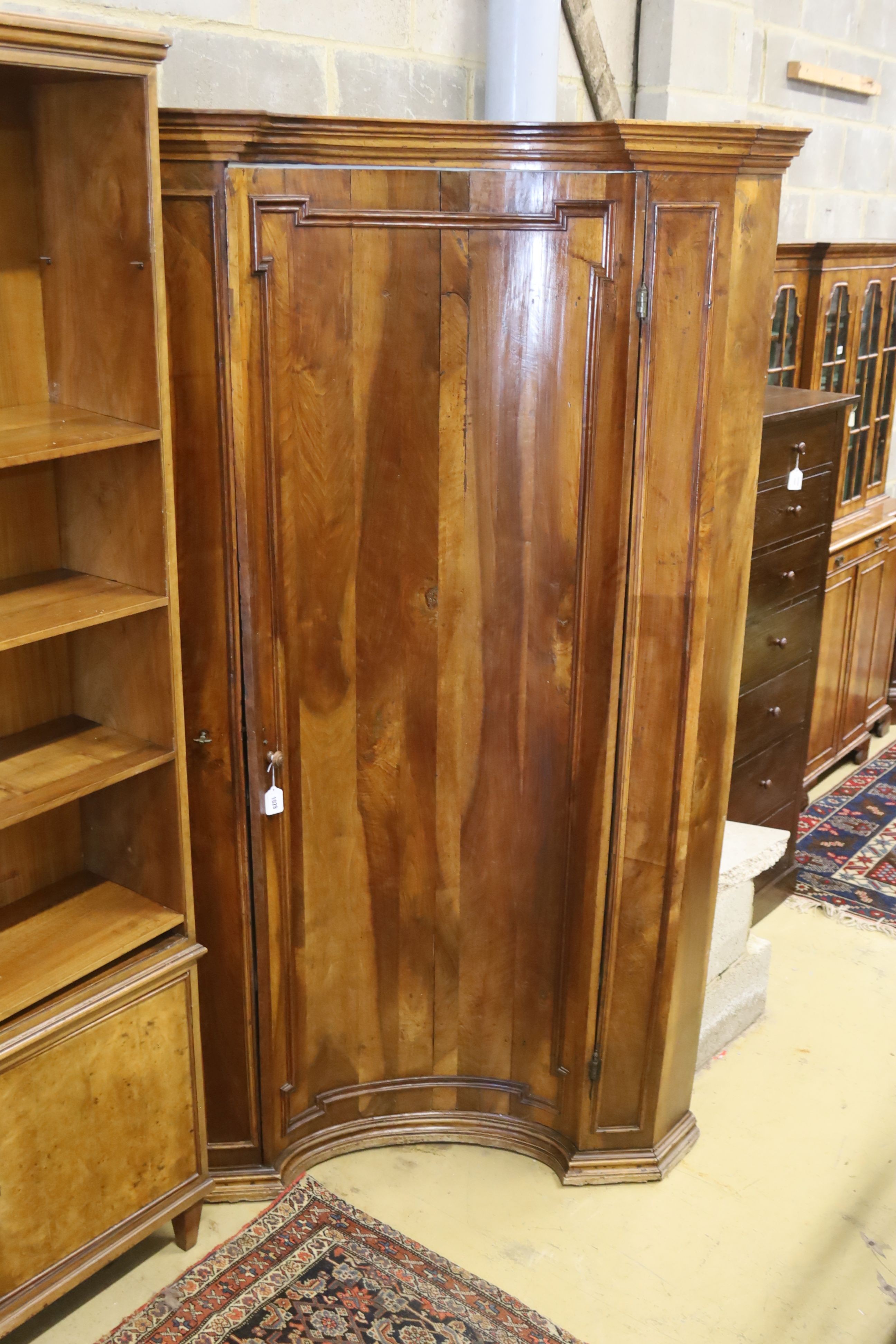 An 18th century North Italian walnut standing corner cupboard with concave door, width 130cm, depth 88cm, height 210cm